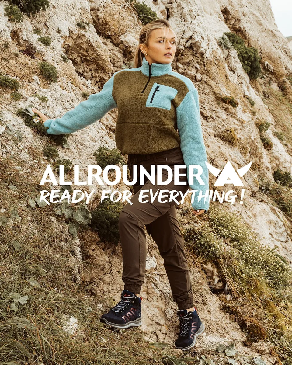 Frau in Fleecejacke an einer Kreidefelswand mit Logo „Allrounder – Ready for everything!“
