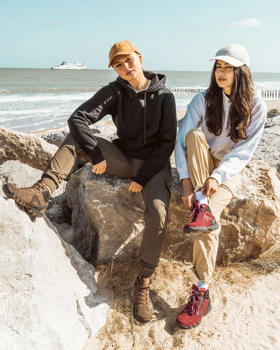 Paar in Outdoor-Kleidung sitzt auf Felsen am Meer, Fotoshooting für die Marke Allrounder