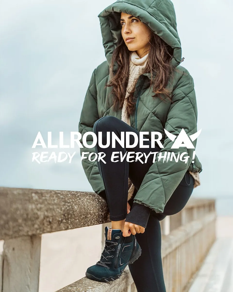 Frau in grüner Winterjacke auf einer Mauer am Meer, Kampagnenmotiv der Marke Allrounder