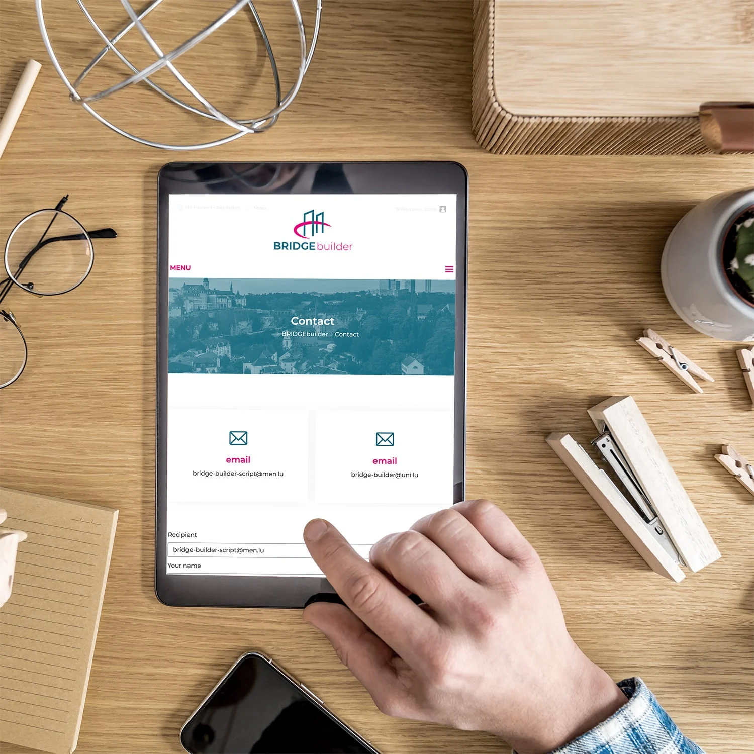 Kontaktseite der Website von bridgebuilder auf einem Tablet auf einem Holztisch