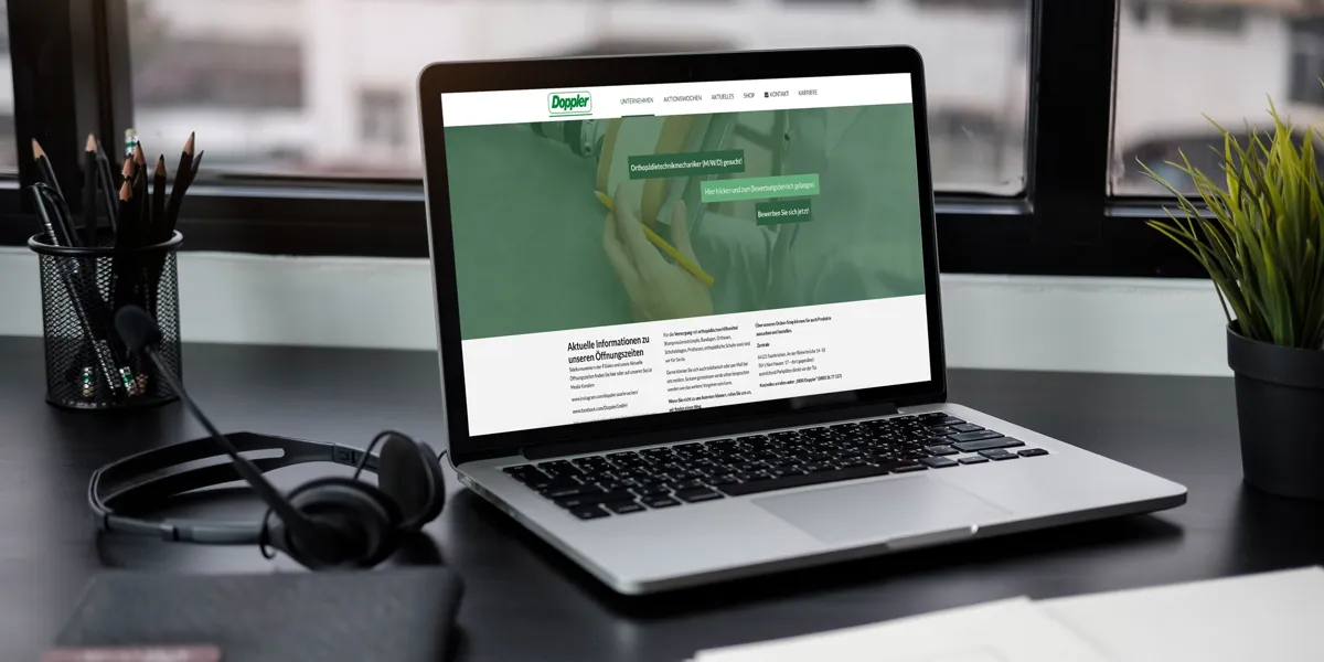 Website der Doppler GmbH auf einem Laptop am Schreibtisch mit Kopfhörern