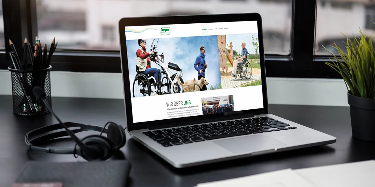 Website von Doppler Reha-Technik mit Rollstuhlfahrern auf einem Laptop am Arbeitsplatz