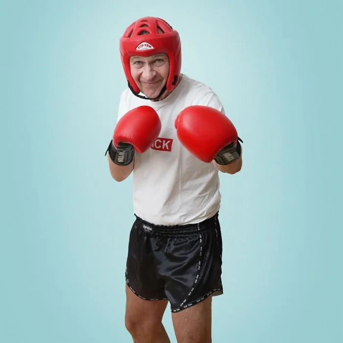 Humorvolles Porträt eines Mannes mit Boxhandschuhen und Kopfschutz für Eisenbeis & Partner