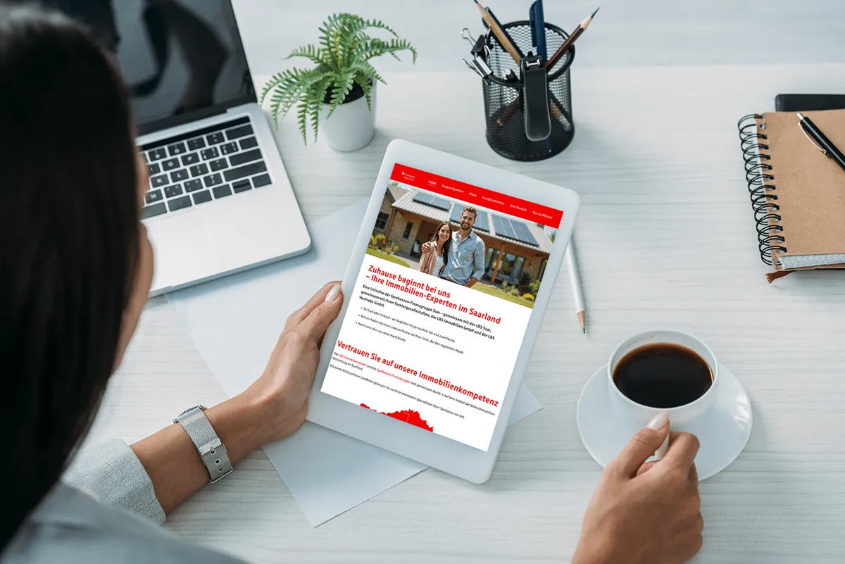 Immobilien-Website der Sparkassen-Finanzgruppe Saar auf einem Tablet, gehalten von einer Frau mit Kaffee
