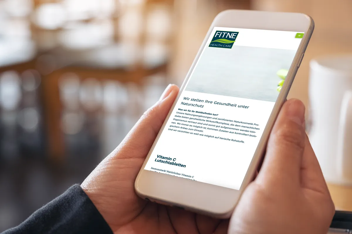 Website von FITNE in der mobilen Ansicht auf einem Smartphone in der Hand