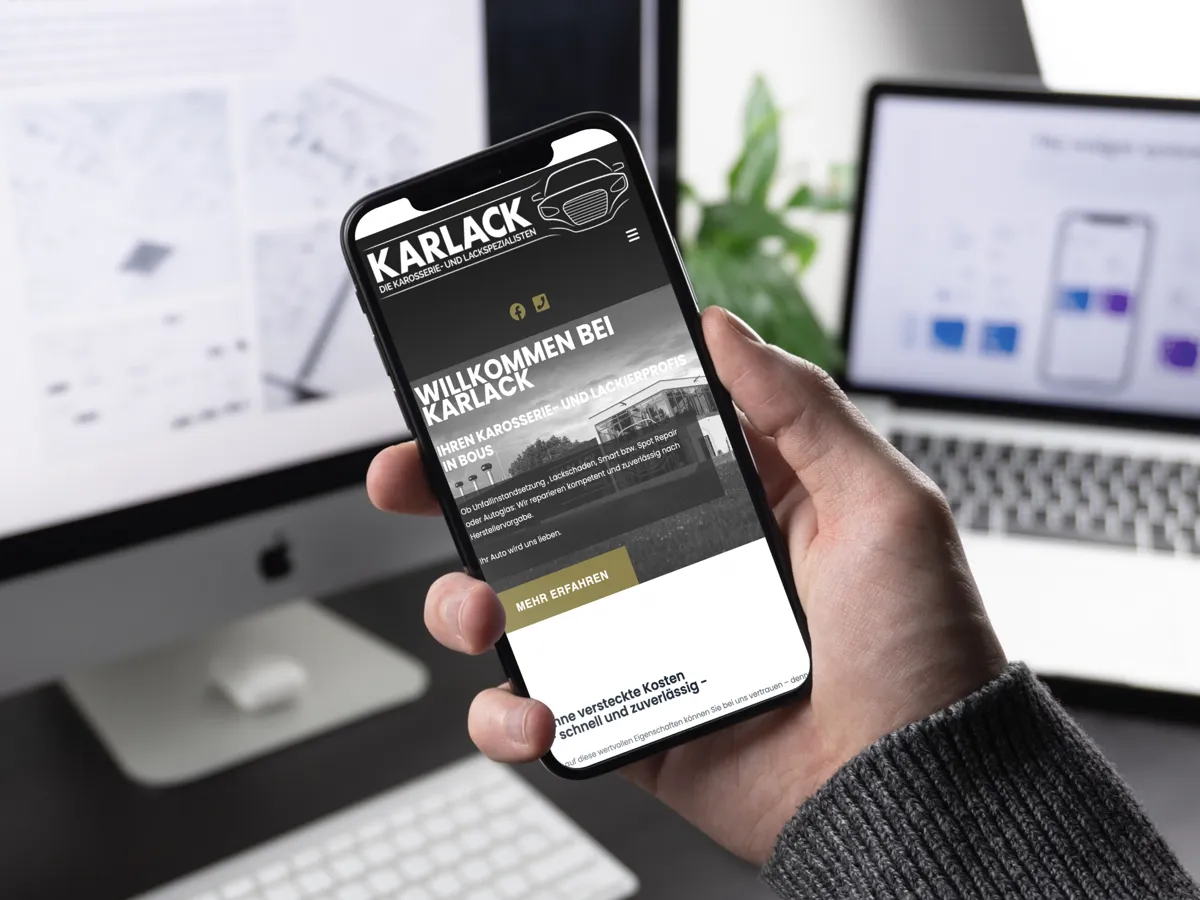 Website von Karlack aus Bous in der mobilen Ansicht auf einem Smartphone vor einem Laptop