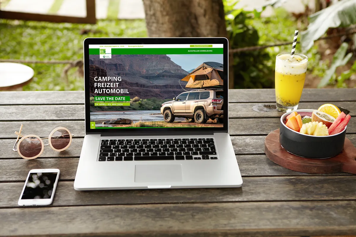 Website der Messe Bexbach auf einem Laptop auf einem Gartentisch mit Saft und Obstschale