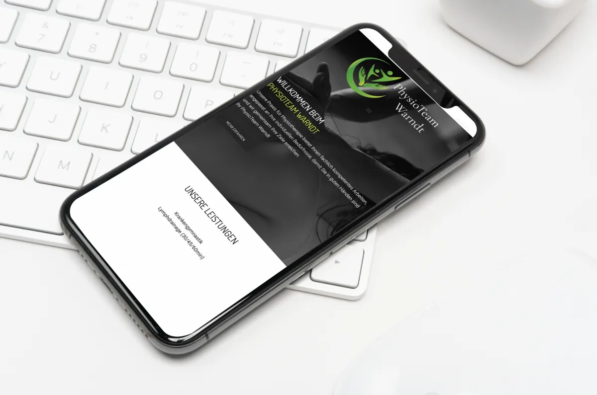 Website des PhysioTeam Warndt aus Ludweiler in der mobilen Ansicht auf einem Smartphone neben Tastatur