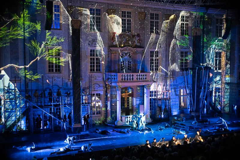 Blau und grün beleuchtete Fassade des Ettlinger Schlosses während einer Abendvorstellung der Schlossfestspiele