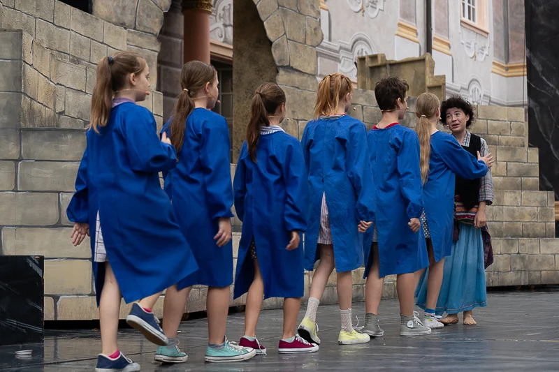 Kinder in blauen Kitteln auf der Bühne der Schlossfestspiele Ettlingen