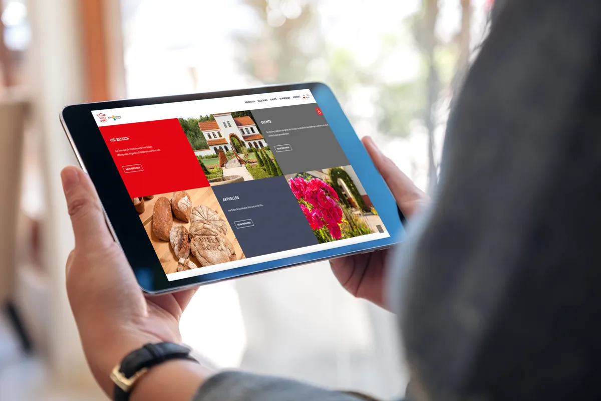 Website der Villa Borg in Perl auf einem Tablet in den Händen einer Person