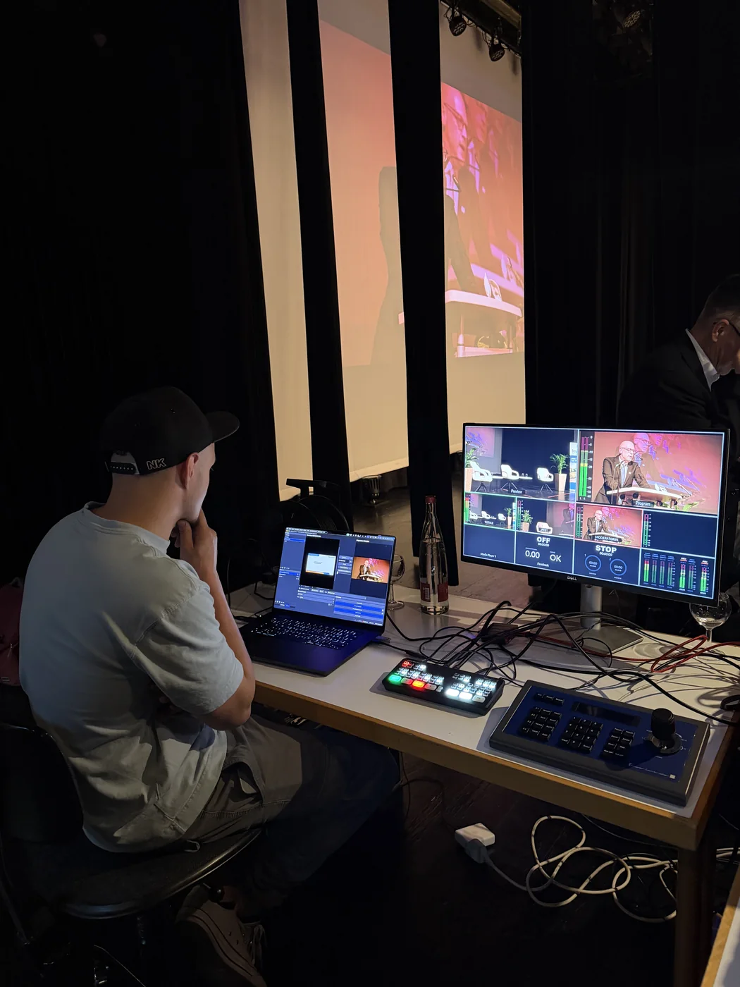 Regieplatz mit Monitoren und Bildmischer während eines Livestreams vor der Bühne