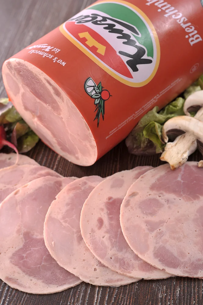 Produktfotografie: aufgeschnittener Bierschinken von Kunzler mit Verpackung, Salat und Champignons