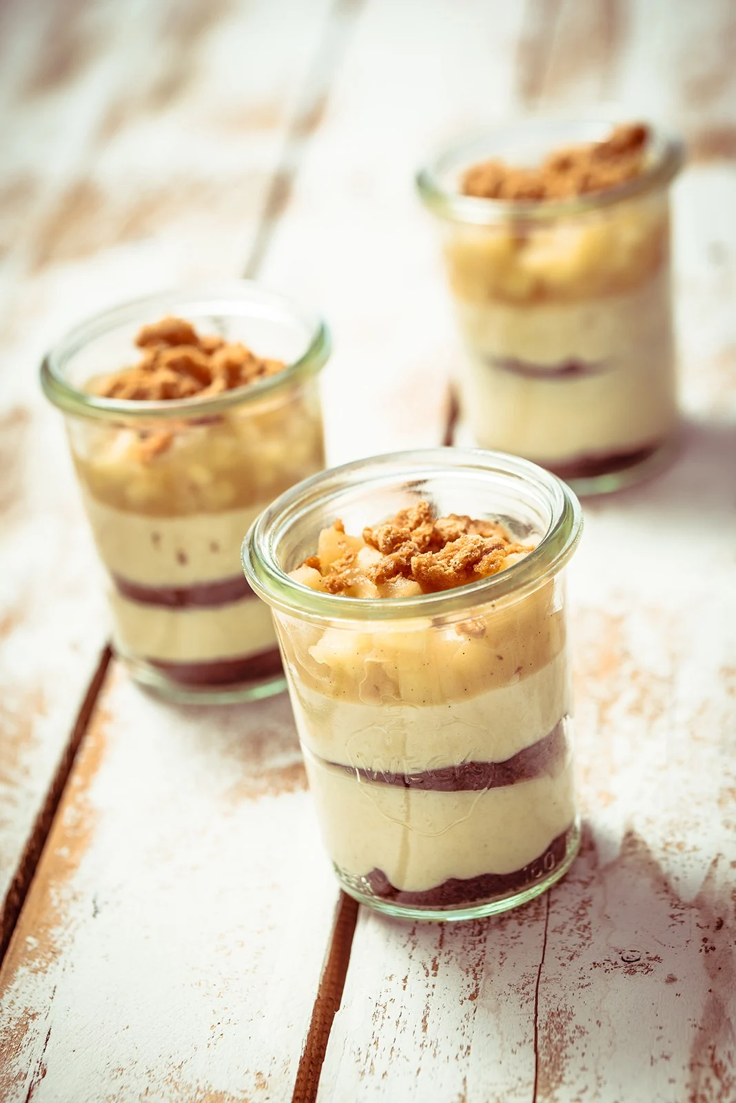 Foodfotografie: drei Desserts mit Crumble im Weckglas auf hellem Holz