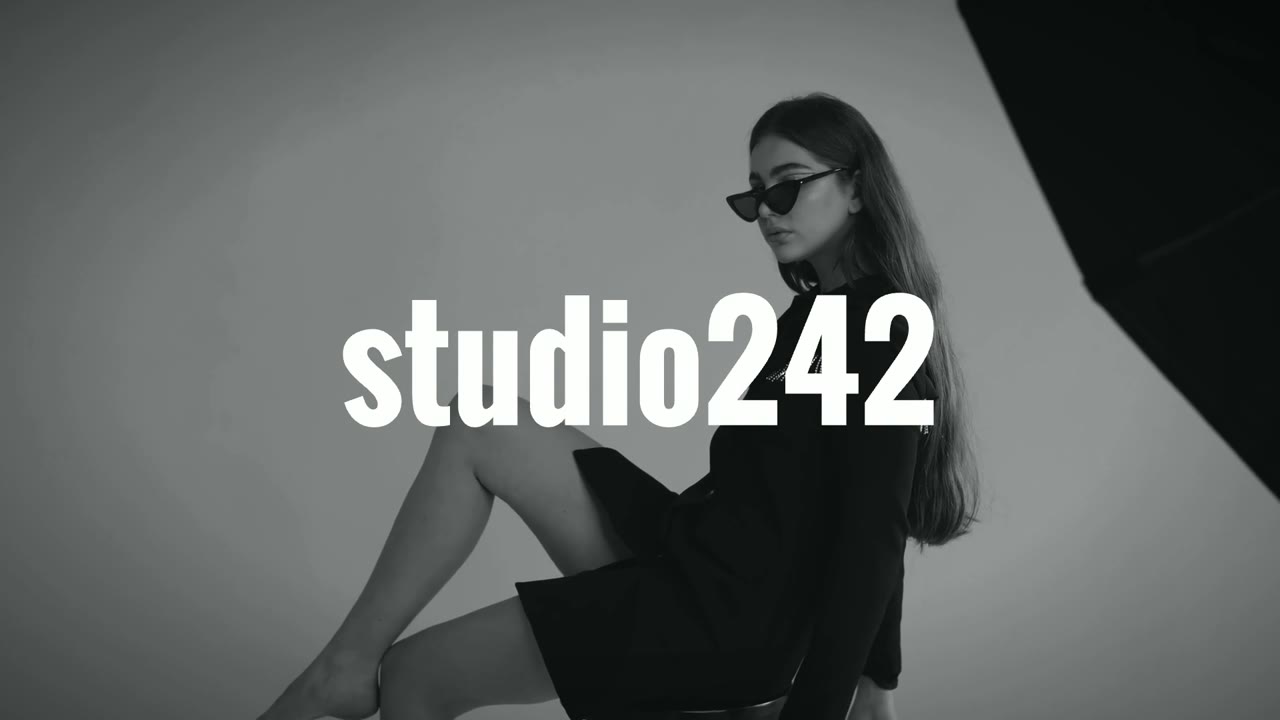 Model mit Sonnenbrille sitzt im Fotostudio studio242 in Völklingen, Schwarz-Weiß-Aufnahme mit Logo